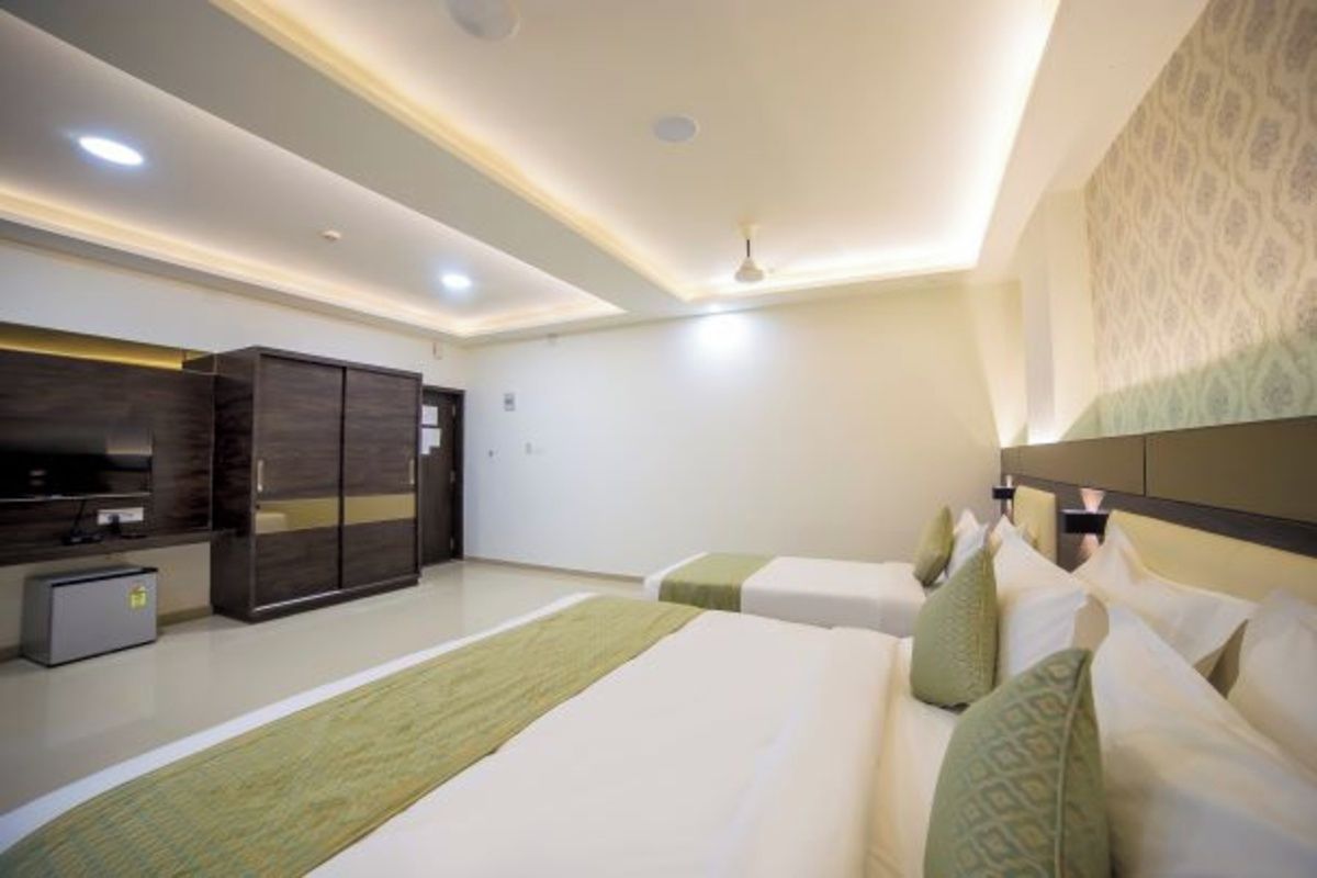 A hotel room with a bed, a desk, a wardrobe, and a television.