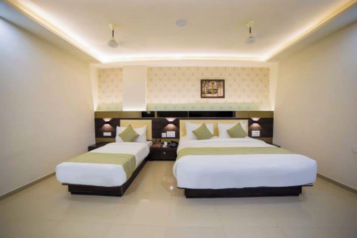 Habitación de hotel con dos camas, una mesita de noche, una lámpara de pared y un aplique de techo.