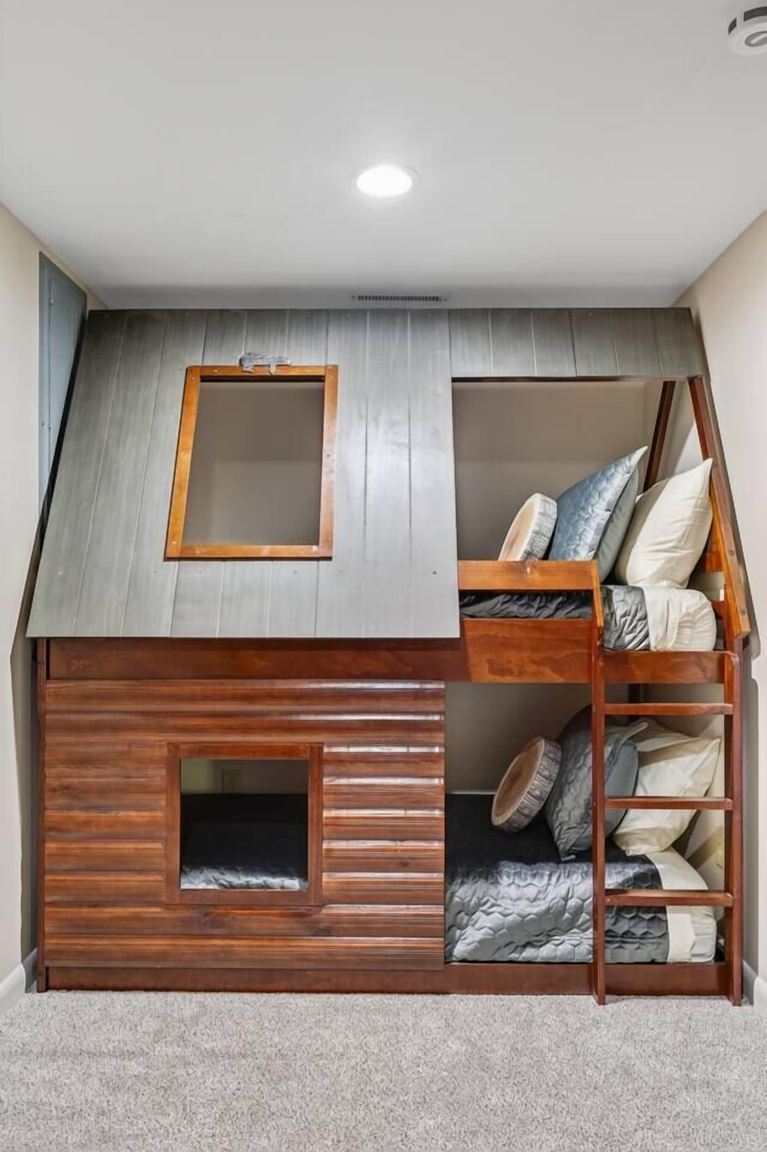Ett sovrum i loftstil med ett sluttande tak, ett fönster och en inbyggd säng med förvaringsutrymme.