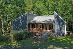 A cabin with a porch, a dining area, and a small outdoor seating space.