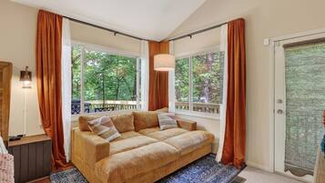 A cozy room with a large window, a sofa, and a lamp.