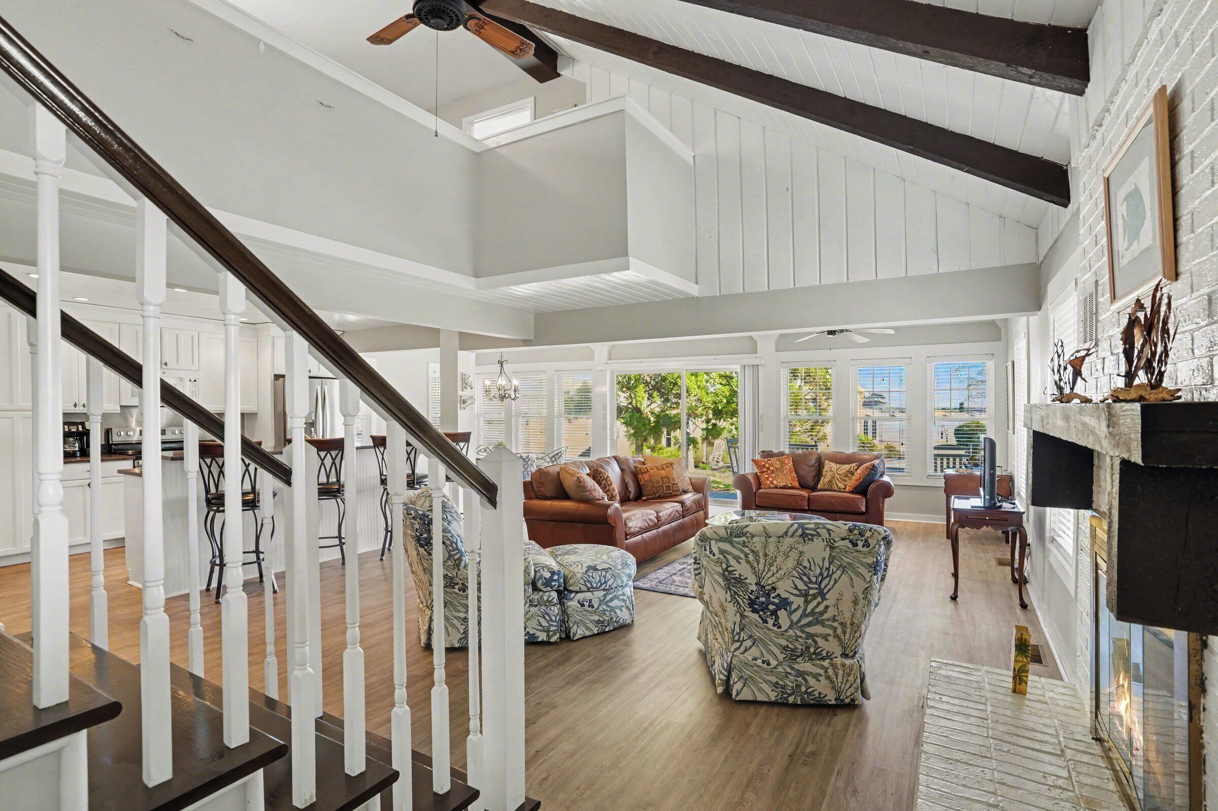 A spacious living area with a staircase, a fireplace, and a view of the outdoors.