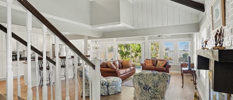 A spacious living area with a staircase, a fireplace, and a view of the outdoors.