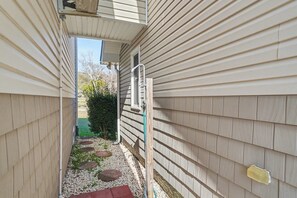 A narrow outdoor corridor with a window and a door, surrounded by siding walls. - Peaceful 4-bedroom cottage in Oyster Bay Golf Community (Sunset Beach)