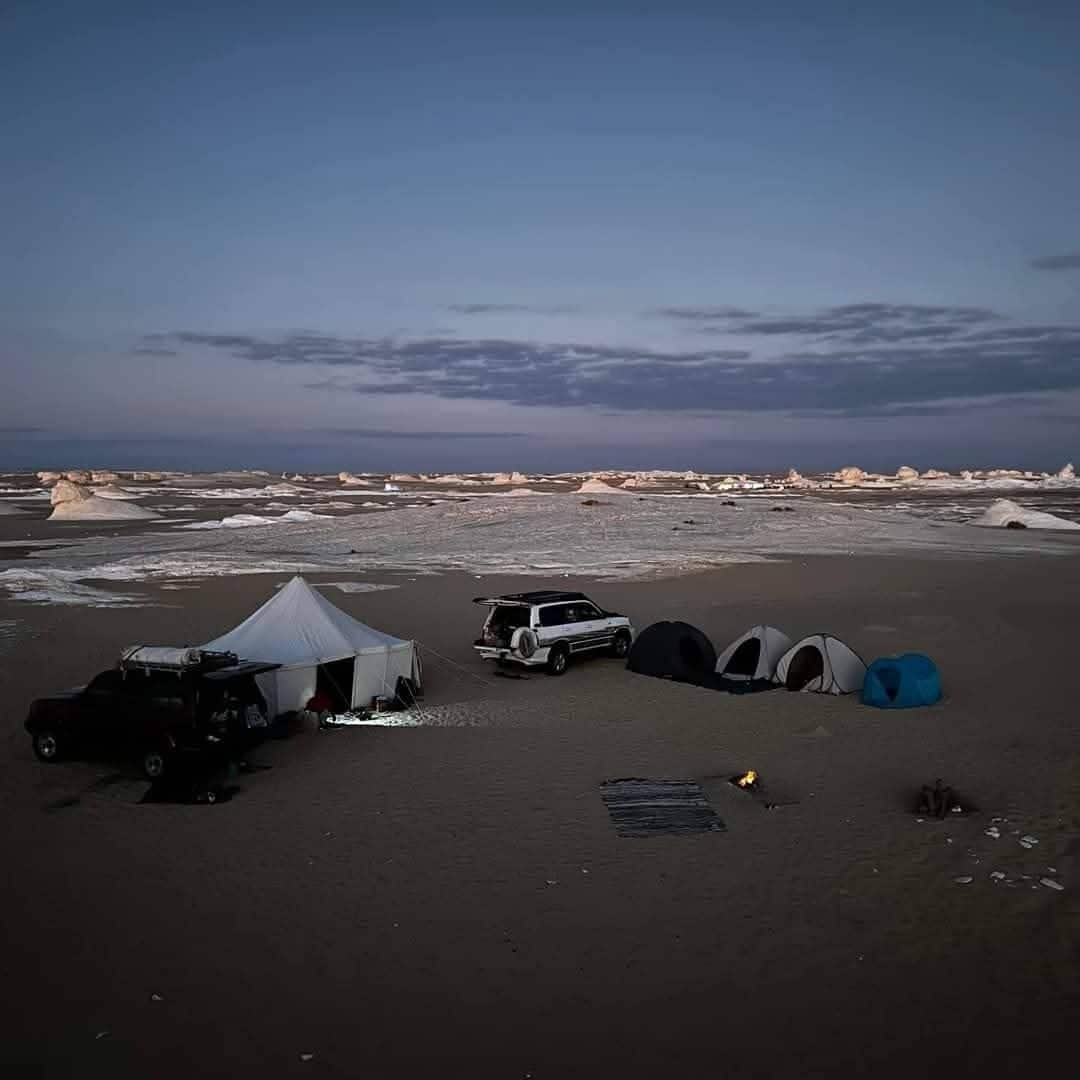 A campsite with tents, a vehicle, and a rocky landscape.