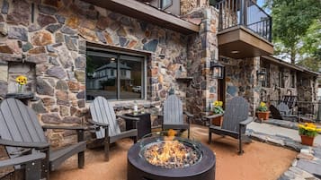 Un bâtiment en pierre doté d’une terrasse, d’un foyer extérieur et d’un balcon.