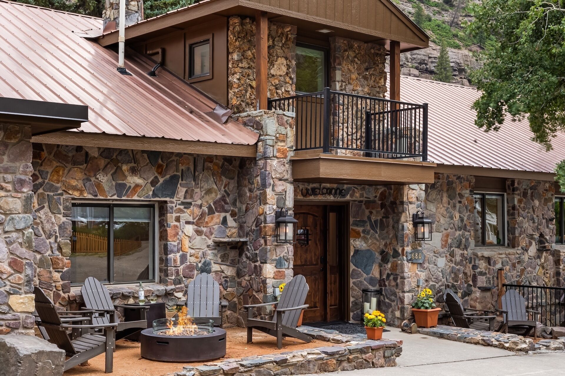 A stone building with a balcony, outdoor seating, and a fire pit.