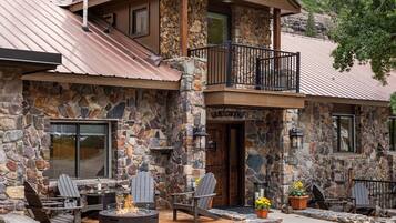 A stone building with a balcony, outdoor seating, and a fire pit.