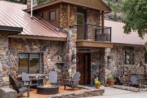 A stone building with a balcony, outdoor seating, and a fire pit.