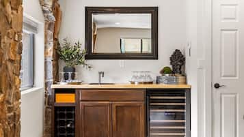 A kitchen with a stone accent wall, a wooden cabinet, a wine rack, and a mirror above the counter.