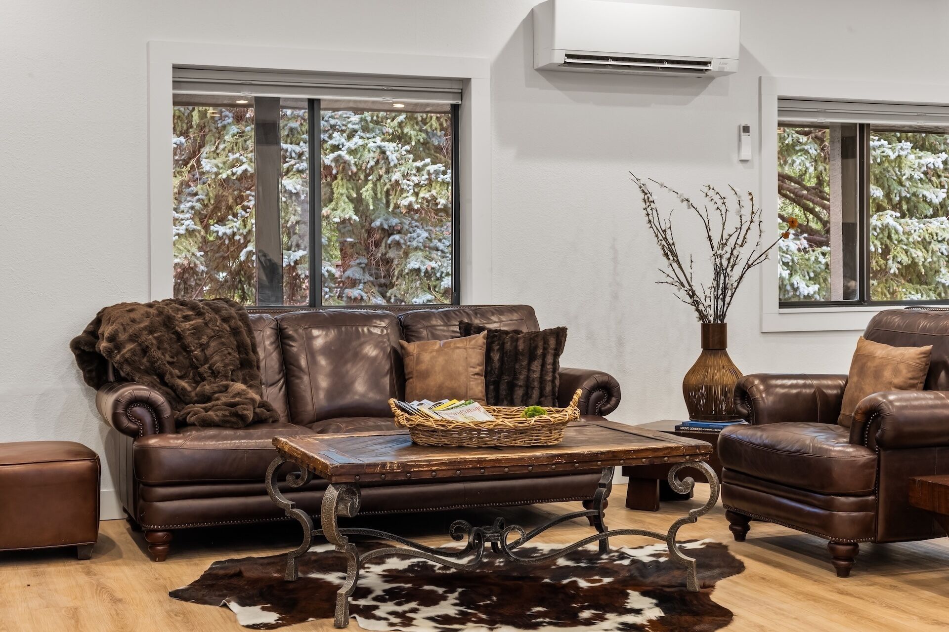 A living room with a brown leather sofa, a coffee table, and a cowhide rug.