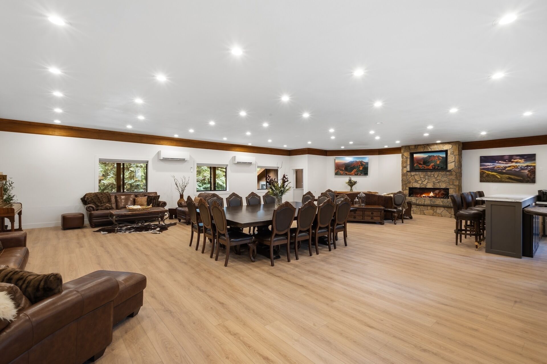 A spacious room with a large dining table, multiple chairs, a fireplace, and a television mounted on a stone wall.