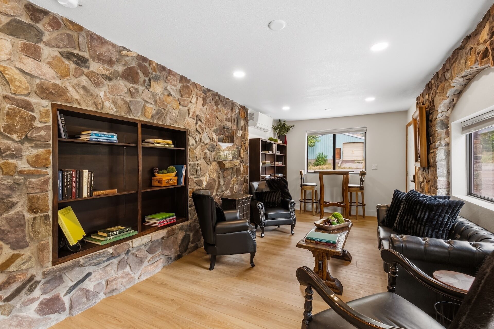 A stone-walled living room with a fireplace, leather sofas, and a dining area with a view.