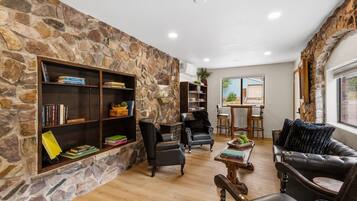 A stone-walled living room with a fireplace, leather sofas, and a dining area with a view.