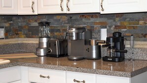 A kitchen with white cabinets, a granite countertop, and various appliances including a toaster, coffee maker, and blender.