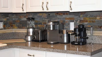 A kitchen with white cabinets, a granite countertop, and various appliances including a toaster, coffee maker, and blender.