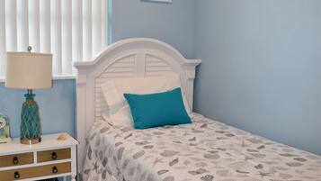 A bedroom with a bed, a nightstand, a lamp, and a wall with a painting.