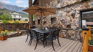 A patio with a table and chairs, a stone wall, and a mountain view.