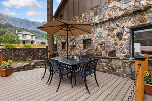 Eine Terrasse mit Tisch und Stühlen, eine Steinsäule und Blick auf die Berge.