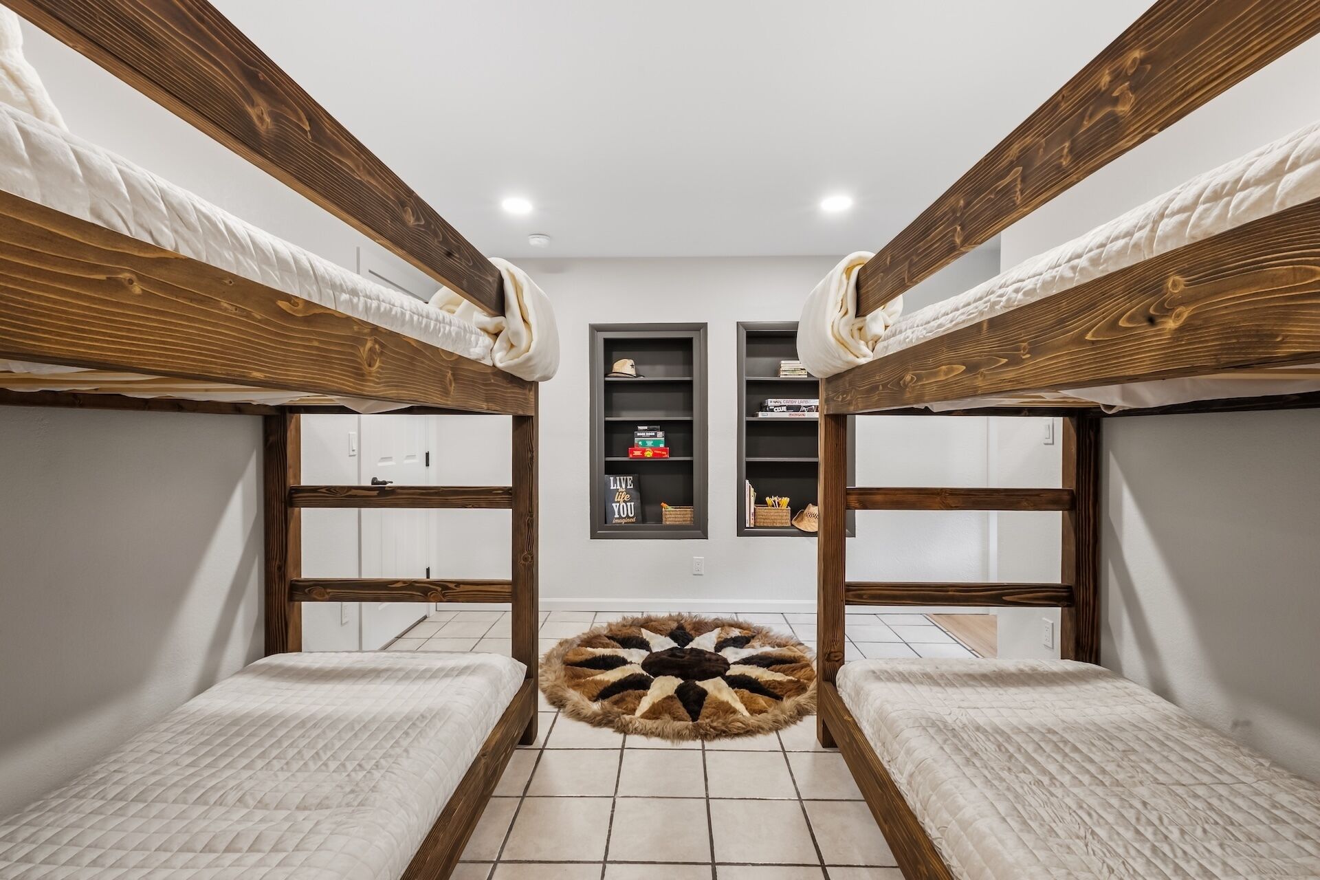 A bunk bed room with a central shelf, a rug, and a door in the background.