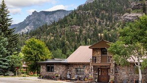 A stone building with a metal roof, a balcony, and a fire pit outside.
