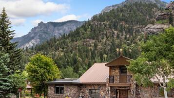 A stone building with a metal roof, a balcony, and a fire pit outside.