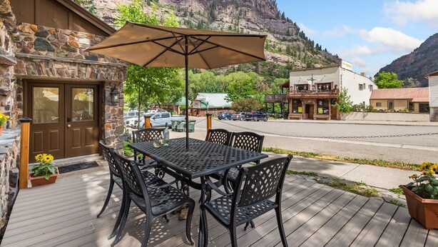 A patio with a table and chairs, a stone wall, and a mountain view.