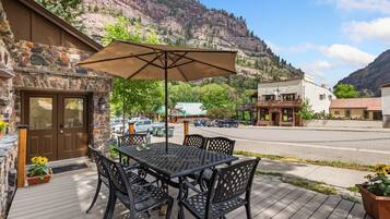 A patio with a table and chairs, a stone wall, and a mountain view.