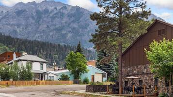 A mountain town with a stone building, a wooden fence, and houses in the foreground.