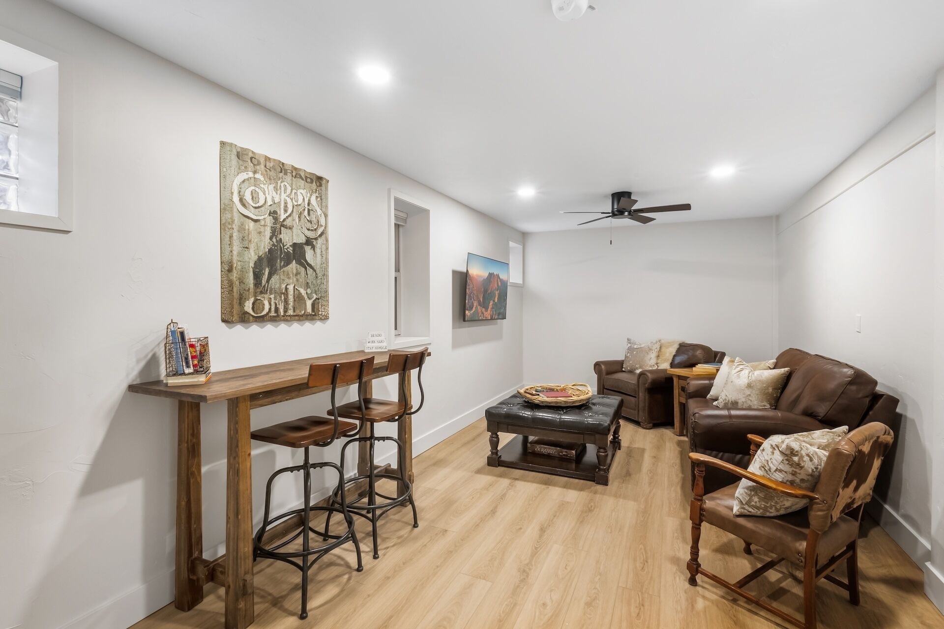 A living room with a wooden coffee table, two chairs, a sofa, and a ceiling fan.