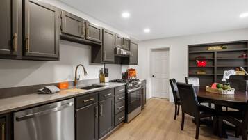 A modern kitchen with dark cabinets, stainless steel appliances, and a dining area with a table and chairs.