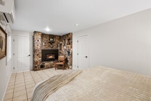 Une chambre avec une cheminée en pierre, un lit et une chaise.