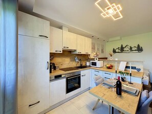 Eine moderne Küche mit weißen Schränken, einer Holz Arbeitsplatte, einem eingebauten Backofen und einem Essbereich mit Tisch und Stühlen.