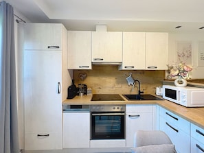Eine moderne Küche mit weißen Schränken, einem eingebauten Backofen, einer Mikrowelle und einem Spülbecken.