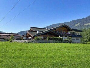 Ein modernes Chalet mit Satteldach, Holzfassade und einem Balkon mit Blumen.