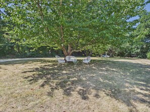 A tree-lined outdoor area with three white chairs under the shade of a large tree. - Fouesnant, family house for 10 with garden (Fouesnant)