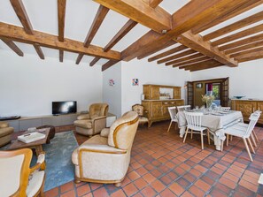 A spacious living area with a high ceiling, a television, comfortable seating, and a dining table set for four. - Fouesnant, family house for 10 with garden (Fouesnant)