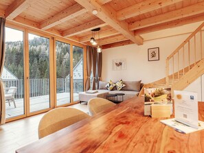 A wooden interior with a sofa, a dining table, and a staircase. - Beautiful private villa for 8 people with TV, terrace and pets allowed (Lachtal)