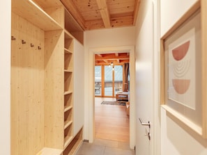 Ein Flur mit Holzbögen, einer Tür mit geometrischem Muster und Blick in einen Essbereich mit Tisch und Stühlen.