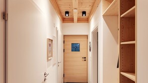 Ein schmaler Korridor mit Holztüren und Fliesenboden, der zu einem Raum mit einer Holztür und einem kleinen Fenster führt.
