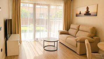 Una sala de estar con un sofá, una mesita redonda y un mueble para televisor.