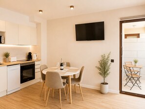 Una cocina moderna con comedor, televisor de pantalla plana y una planta en maceta.