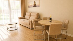 A living room with a sofa, a round table, and a bottle of champagne. - Luxury Cubelles Aparthotel (Cubelles)