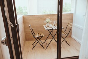 Un balcón de madera con una mesa, sillas, un florero con flores y una vela.