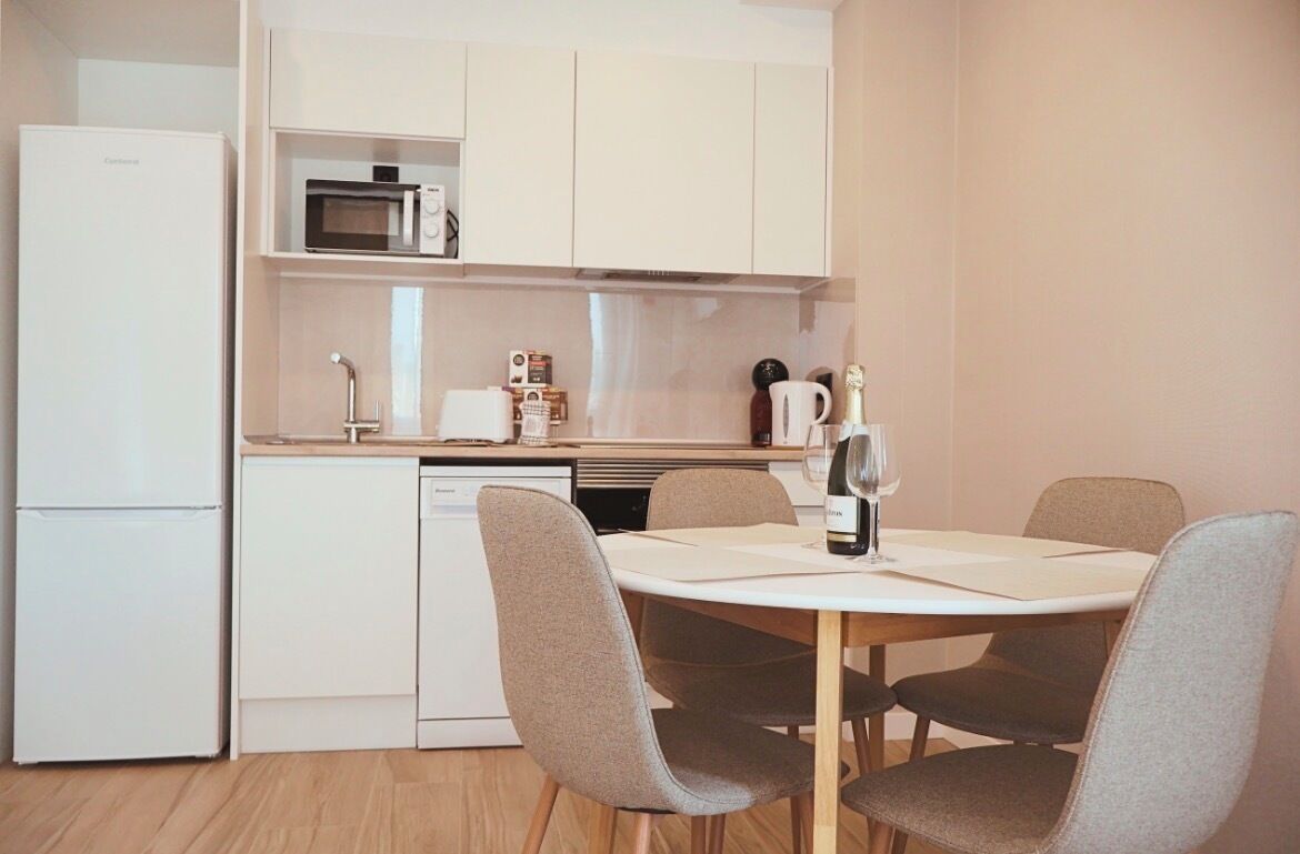 A compact kitchen with a microwave, coffee machine, and a wine bottle on the counter.