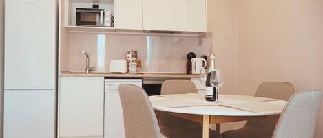 A compact kitchen with a microwave, coffee machine, and a wine bottle on the counter.