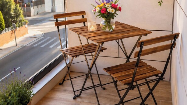 A balcony with a wooden table and chairs, a vase of flowers, and a hanging plant. - Luxury Cubelles Aparthotel (Cubelles)