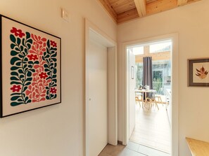 Ein Flur mit einem gerahmten Blumenbild, einer Tür zu einem Essbereich mit Tisch und Stühlen sowie einem gerahmten Blattgemälde an der Wand.