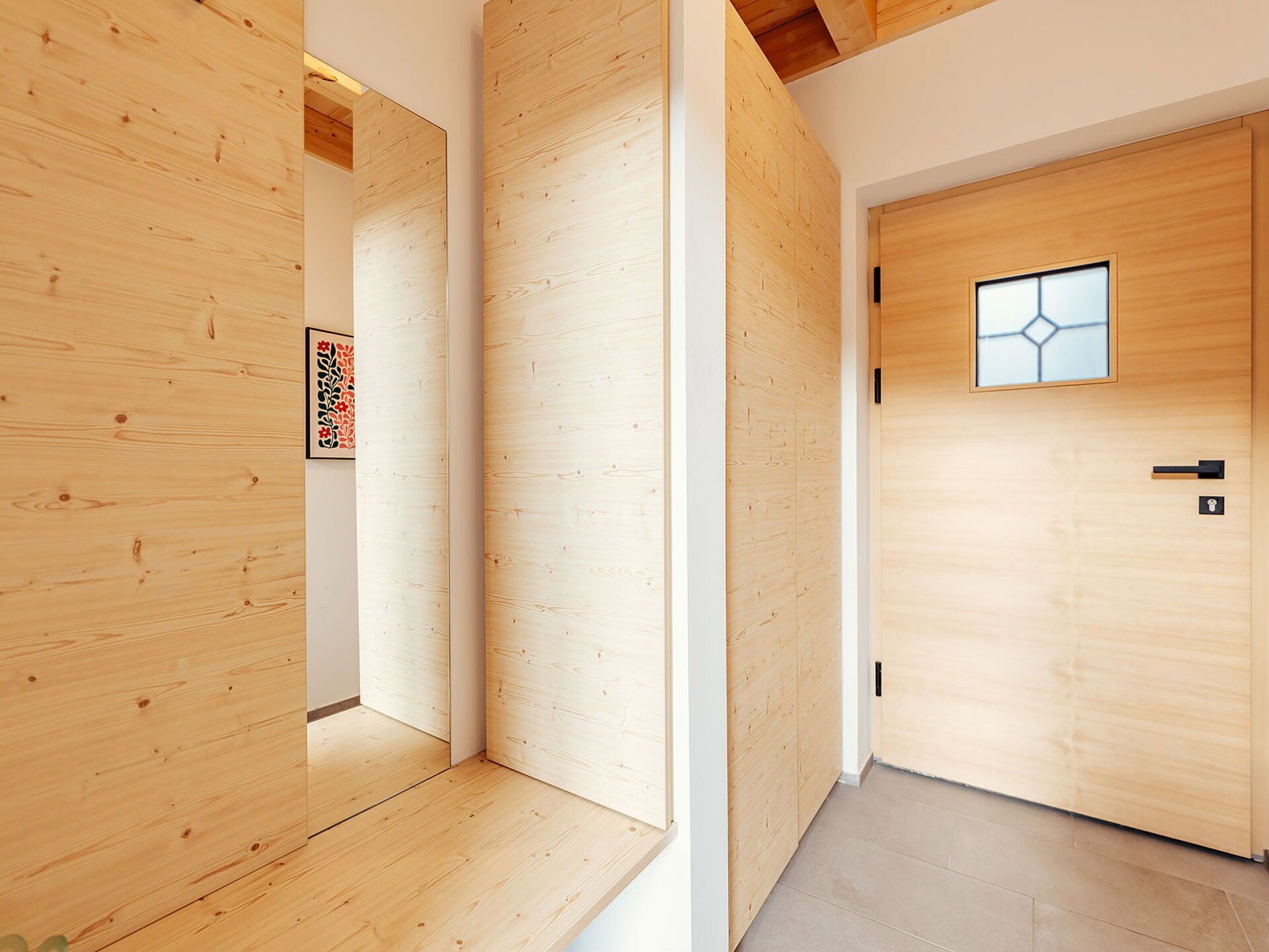 A hallway with wooden walls and a door with a geometric window design.