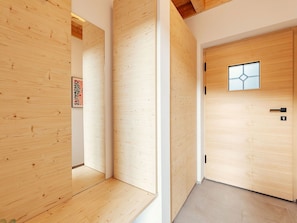 Ein Korridor mit Holzwänden und einer Tür mit einem geometrischen Fensterdesign.